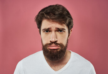 Obraz premium Man with a beard on a pink background sad face emotions model