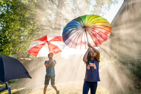 Girl with rainbow umbrella in water mist