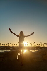 Fototapeta premium silhouette of woman with open arms at sunset seaside beach