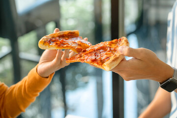 Hands holding slice of pizza having party at home..