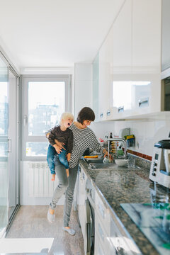 Mother with kid washing dishes in kitchen