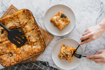 person cutting piece of lasagna