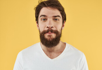 Fototapeta premium Close-up portrait of a happy man in a white t-shirt on a yellow background