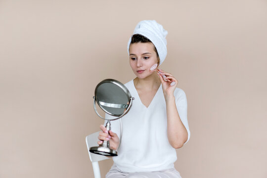 Woman doing facial massage with stone in bathroom