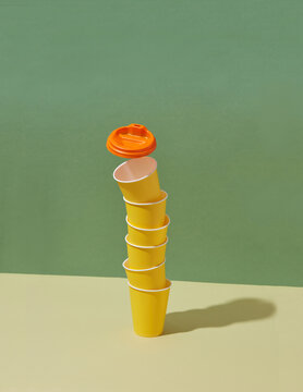 Stack of paper disposable cups with flying plastic cap.