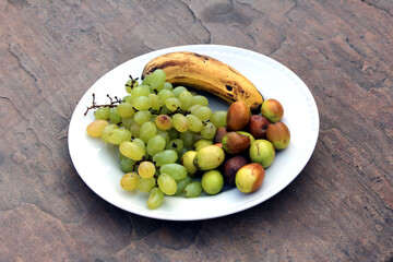 some fresh sweet fruits put in a white plate isolated on stone background