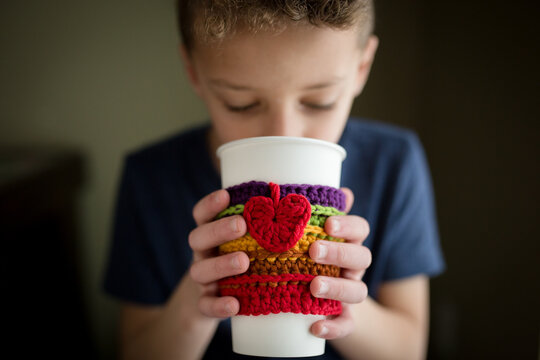 Boy holds cup with crocheted cozy