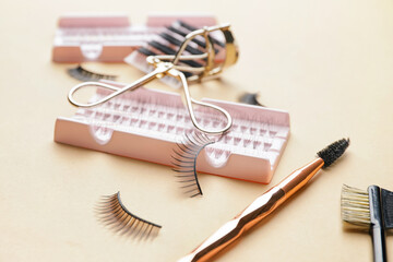 Composition with false eyelashes and tools on color background, closeup