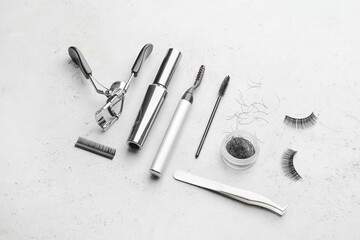 Composition with false eyelashes and tools on light background