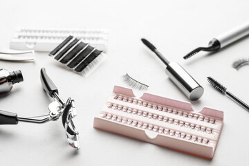 Composition with false eyelashes and tools on light background, closeup