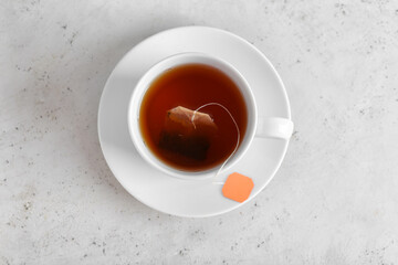 Cup of aromatic black tea on light background