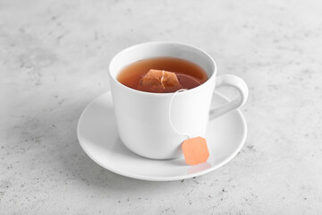 Cup of aromatic black tea on light background