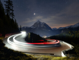 Light trails on narrow bend on mountain pass road.