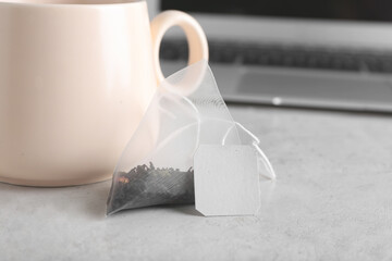 Bag with aromatic black tea on light background