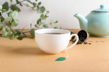 Cup of aromatic black tea on color background