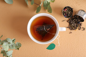 Cup of aromatic black tea on color background