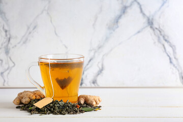 Cup of aromatic black tea on light background