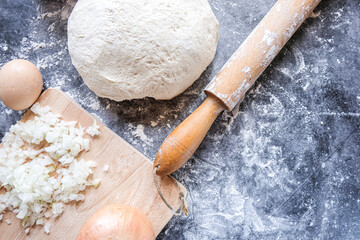 The ingredients for baking cakes with meat-tat. A dish of national Tatar and Bashkir cuisine. Ground beef, dough, eggs, onions. Gray background.