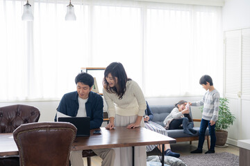 テレワークをする両親とリビングで過ごす子供たち