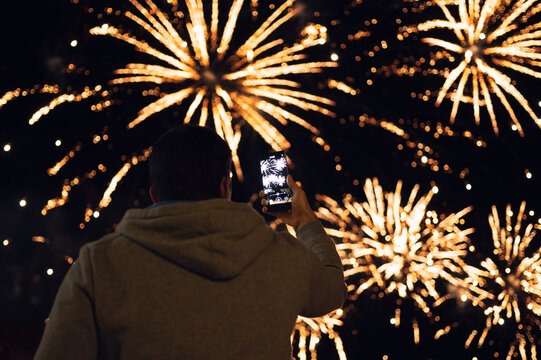 Young man photographing fireworks culmination using smartphone