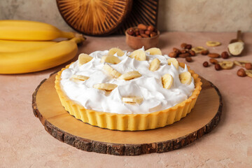 Board with tasty banana pie on color background