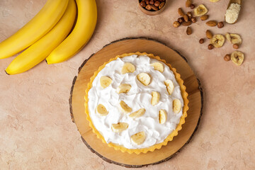 Board with tasty banana pie on color background