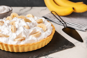 Board with tasty banana pie on table