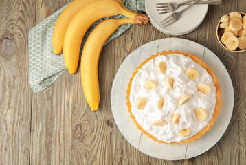 Board with tasty banana pie on wooden background