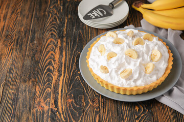 Plate with tasty banana pie on wooden background