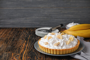 Plate with tasty banana pie on wooden background