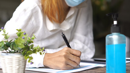 Planner plan and write Schedule Calendar and reminder agenda, work online at home. Close up of woman hand wear mask planning daily appointment and note holiday trip in diary at office desk.