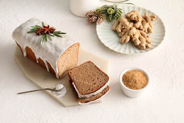 Board with tasty gingerbread cake on light background