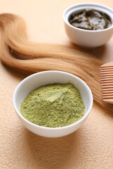Bowls with henna, hair and comb on color background, closeup