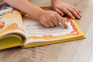 Children's hands. A child reads a book. Close-up shot. A child's hand. An open book.