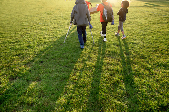 Boy on crutches walks with friends
