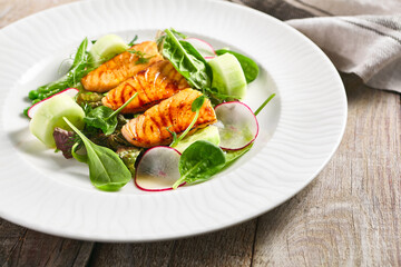 Salmon Salad with Fresh Vegetables. White plate with healthy fish food on wooden table. Healthy, Vegetarian, Restaurant rustic food concept.