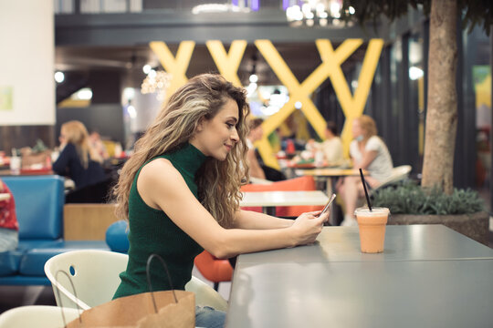 Young Woman sitting in a Food Court of Shopping Mall