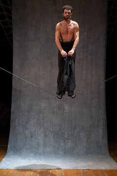 Shirtless man standing still on a slackwire