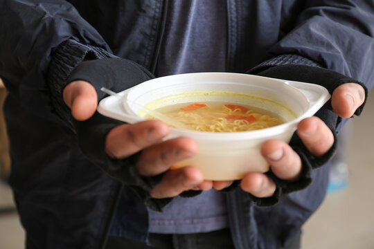 Poor homeless man with hot food in warming center, closeup