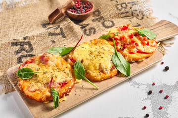 Mini pizza board on rustic white table. Pizza with cheese and tomatoes garnish with basil leaf. Small food concept.