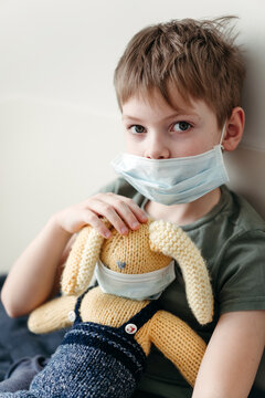 A little boy with a toy in a protective medical mask.