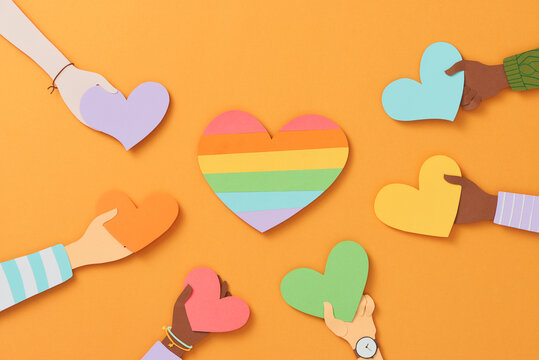 Different color hands holding colorful heart