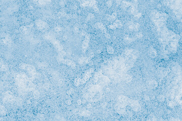 Blue tone, textured ice surface with air bubbles inside.