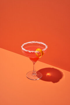 Cocktail glass standing against orange background