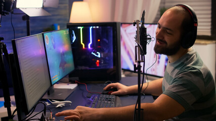 Streamer cyber performing space shooter video game on powerful pc talking with players on chat open during professional competition. Player man using professional headphones in streaming home studio