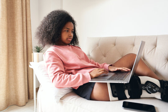 African American teenager with injury using laptop