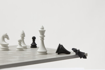 Defeated and falling black chess king by a white king.