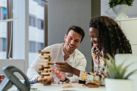 Cheerful colleagues playing Jenga game at workplace