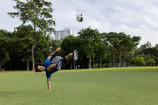 Freestyle footballer in Park flips the ball up high in the air