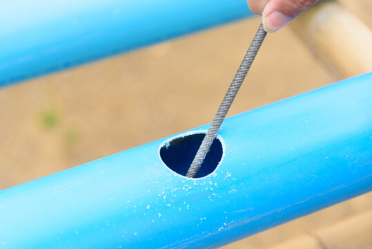 The man use rasp scratch the hole at blue PVC pipe